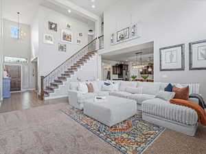 Living area with a chandelier, a high ceiling, stairway, wood finished floors, and recessed lighting