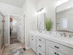 Bathroom with a shower stall, double vanity, and light tile patterned floors