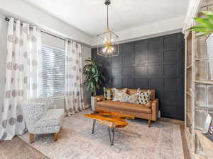 Living area featuring a decorative wall, carpet, and a chandelier