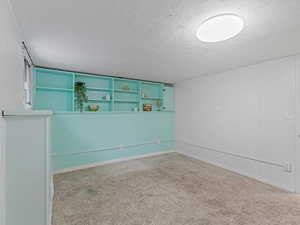 Empty room featuring a textured ceiling and light colored carpet