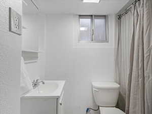 Bathroom with a textured wall, vanity, and curtained shower