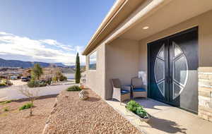 View of exterior entry with french doors, a mountain view, and stucco siding
