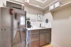 Kitchen with freestanding refrigerator, light countertops, dark brown cabinetry, and light wood finished floors