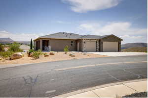 Ranch-style home featuring stone siding, a garage, stucco siding, concrete driveway, and a mountain view