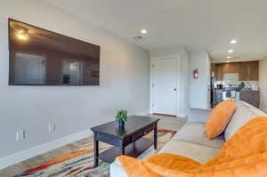 Living room with light wood-style flooring and recessed lighting