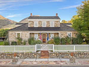 Traditional-style house with a high end roof, stone siding, a porch, and a chimney