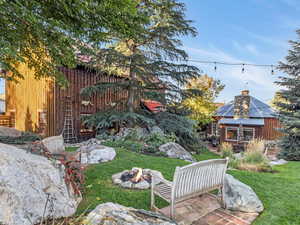 View of green lawn with an outdoor fire pit and a patio area