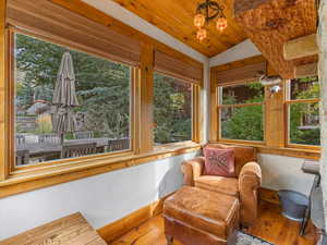 Sunroom / solarium with vaulted ceiling, hardwood / wood-style floors, and wood ceiling
