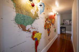 Hardwood flooring throughout a hallway featuring an accent wall with a world map graphic