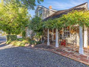 Rear view of house with stone siding, a chimney, and a patio