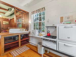 Kitchen featuring light wood-style floors, wooden walls, black microwave, and butcher block counters