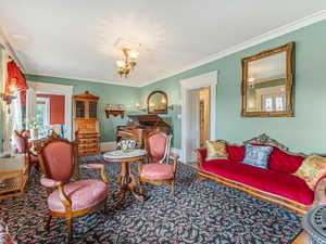 Living area with ornamental molding and a chandelier