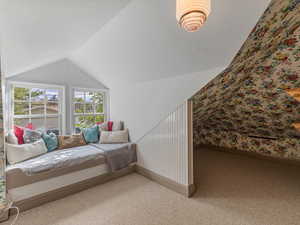 Carpeted bedroom featuring vaulted ceiling and wallpapered walls