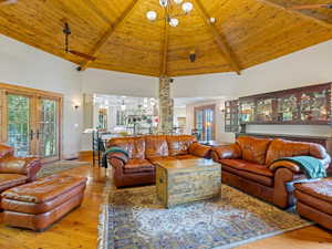 Living room with french doors, a towering ceiling, hardwood / wood-style floors, healthy amount of natural light, and a wood ceiling with exposed beams