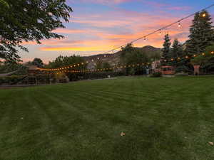 Yard at dusk featuring a lawn and a mountain view