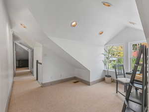 Additional living space featuring vaulted ceiling, light colored carpet, and recessed lighting