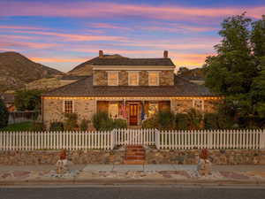 View of front of house with stone siding, a porch, a chimney, and a fenced front yard