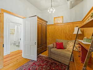 Living area with wood-type flooring, wooden walls, and a chandelier