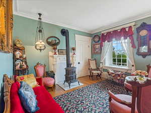 Living room with a wood stove, light wood-type flooring, and crown molding