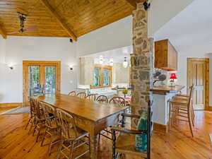 Dining area featuring high vaulted ceiling, light wood-style flooring, french doors, a wood ceiling with exposed beams, and ceiling fan