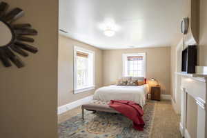 Bedroom featuring two windows with wood blinds, neutral wall tones, and crown molding