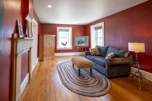 Spacious room featuring wood-finish flooring, two windows, and a decorative mantel