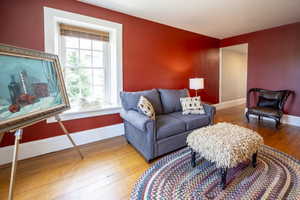 Room featuring wood-finish flooring with a braided area rug, a white trim window with blinds, and a spacious doorway