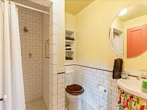 Mother in law 2nd Full bath featuring tile walls, a stall shower, a wainscoted wall, and tile patterned floors