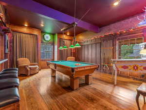 Garage now Recreation room with hardwood / wood-style floors, pool table, plenty of natural light, beam ceiling, and wooden walls
