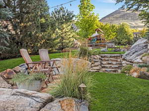 View of grassy yard featuring an outdoor fire pit