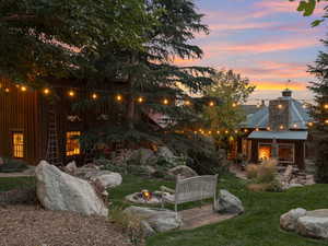 Yard at dusk featuring a patio and a lawn