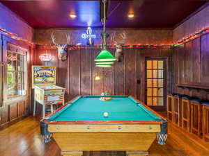 Garage now Playroom featuring pool table, hardwood / wood-style flooring, and wooden walls