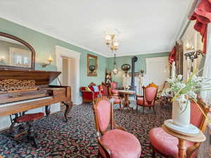 Living area with a wood stove, ornamental molding, and carpet flooring