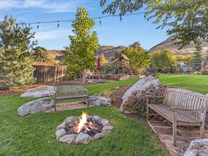 View of yard featuring a playground, a mountain view, and an outdoor fire pit