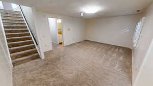 Empty room with stairs and light colored carpet