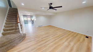 Unfurnished living room featuring light wood-type flooring, recessed lighting, stairway, and ceiling fan