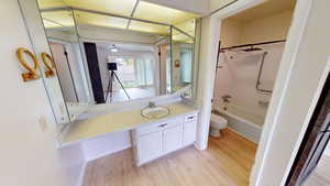 Full bathroom with bathing tub / shower combination, light wood-style floors, vanity, and a ceiling fan