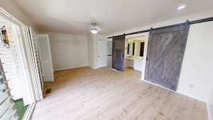 Unfurnished bedroom with light wood-style flooring, connected bathroom, and ceiling fan