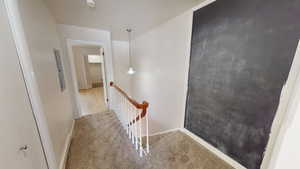 Corridor with an upstairs landing, carpet floors, and electric panel