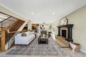 Living area with crown molding, recessed lighting, stairs, Travertine tile floors, and a fireplace with raised hearth