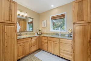 Primary en suite full bathroom with natural light, light tile patterned floors, and double vanity