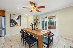 Dining room with Travertine tile floors, crown molding, recessed lighting, and sliding glass door access to the sunroom