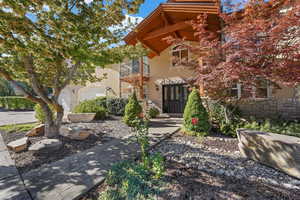 View of front facade featuring a balcony, stone siding, and stucco siding