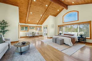 Primary Bedroom with high vaulted, wooden ceiling with exposed beams, light hardwood floors, recessed lighting, and access to 2 decks.