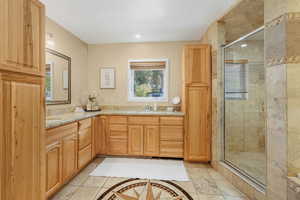 Primary en suite full bathroom with natural light, double vanity, and inlaid floor details