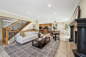 Living area featuring crown molding, recessed lighting, Travertine tile floors, stairway, and a premium fireplace