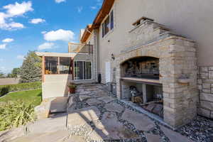 View of patio / terrace featuring a sunroom and an outdoor stone fireplace