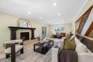 Living room featuring crown molding, Travertine tile floors, recessed lighting, a high end fireplace, stairs, and a sliding glass door to the sunroom