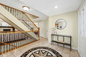 Entrance foyer with light tile patterned floors, a fireplace, inlaid floor details, recessed lighting, and stairs