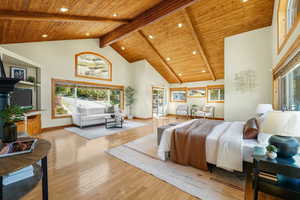 Bedroom with high vaulted, wooden ceiling with exposed beams, light hardwood floors, and recessed lighting